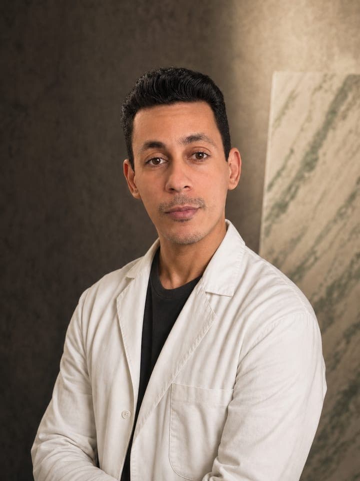 Gabriel Coelho Ferreira, de bata branca, junto a um painel de efeito mármore